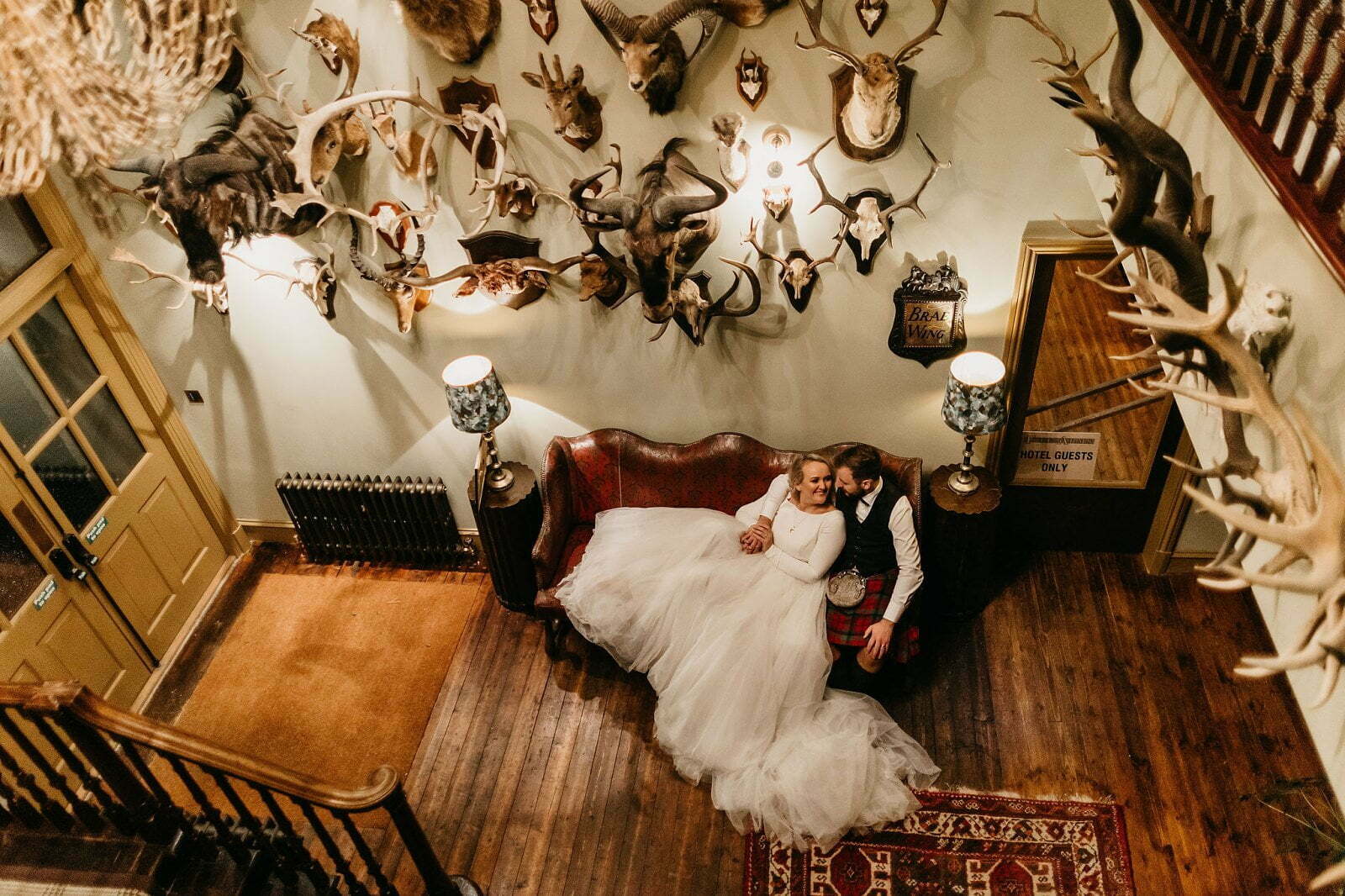 fife arms hotel braemar luxury micro wedding venue bride groom portraits on couch under antlers smiling